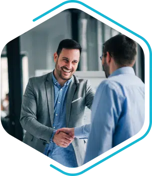 Two men in business attire shake hands and smile in a modern office setting, successfully finalizing an engineering change management agreement.